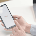 Person holding phone. The Google logo is on the screen, depicting Google Search.
