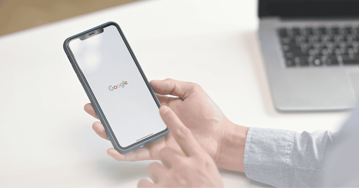 Person holding phone. The Google logo is on the screen, depicting Google Search.